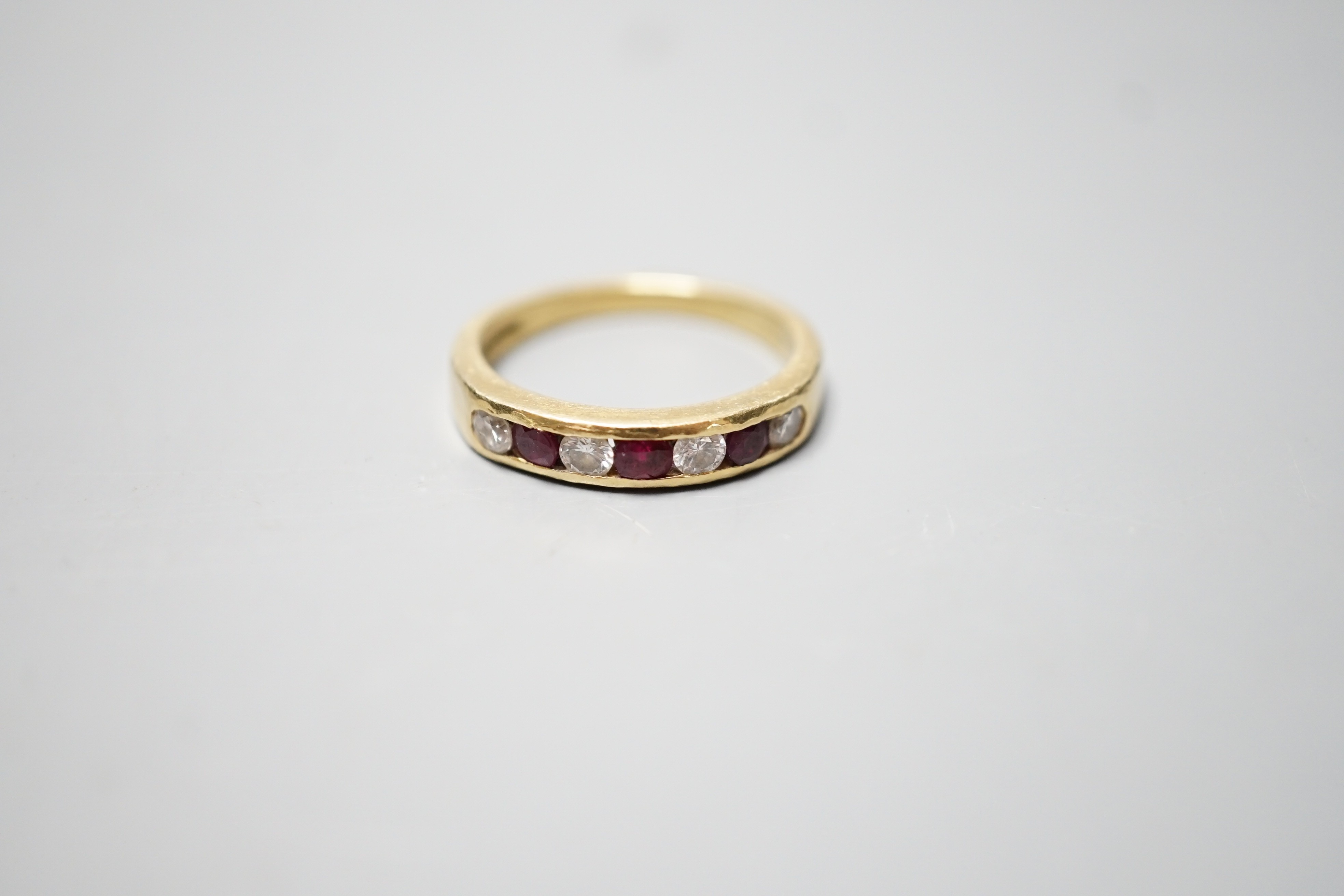 A modern 18ct gold and channel set four stone diamond and three stone ruby set half hoop ring, size N, gross weight 4.3 grams.